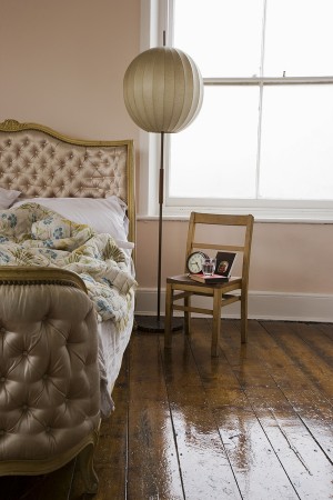 Chair and circular lampshade besides a cropped bed in bedroom